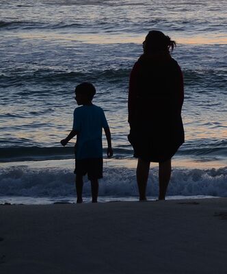 Mutter und Sohn von hinten an einem Sandstrand